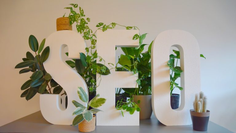 A modern SEO workspace with lush green plants surrounding SEO letters