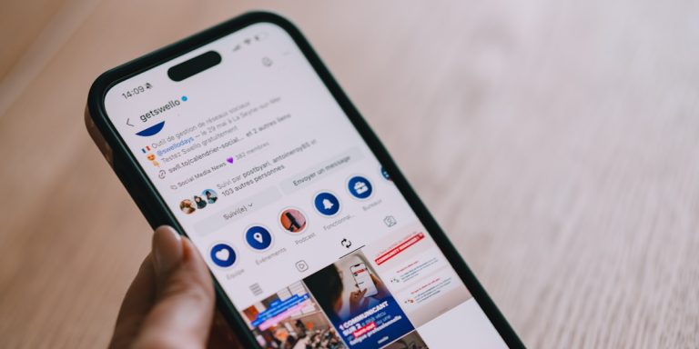 Hand holding smartphone displaying social media feed