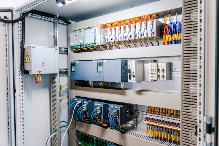 Open industrial electrical control panel with wires and modules.